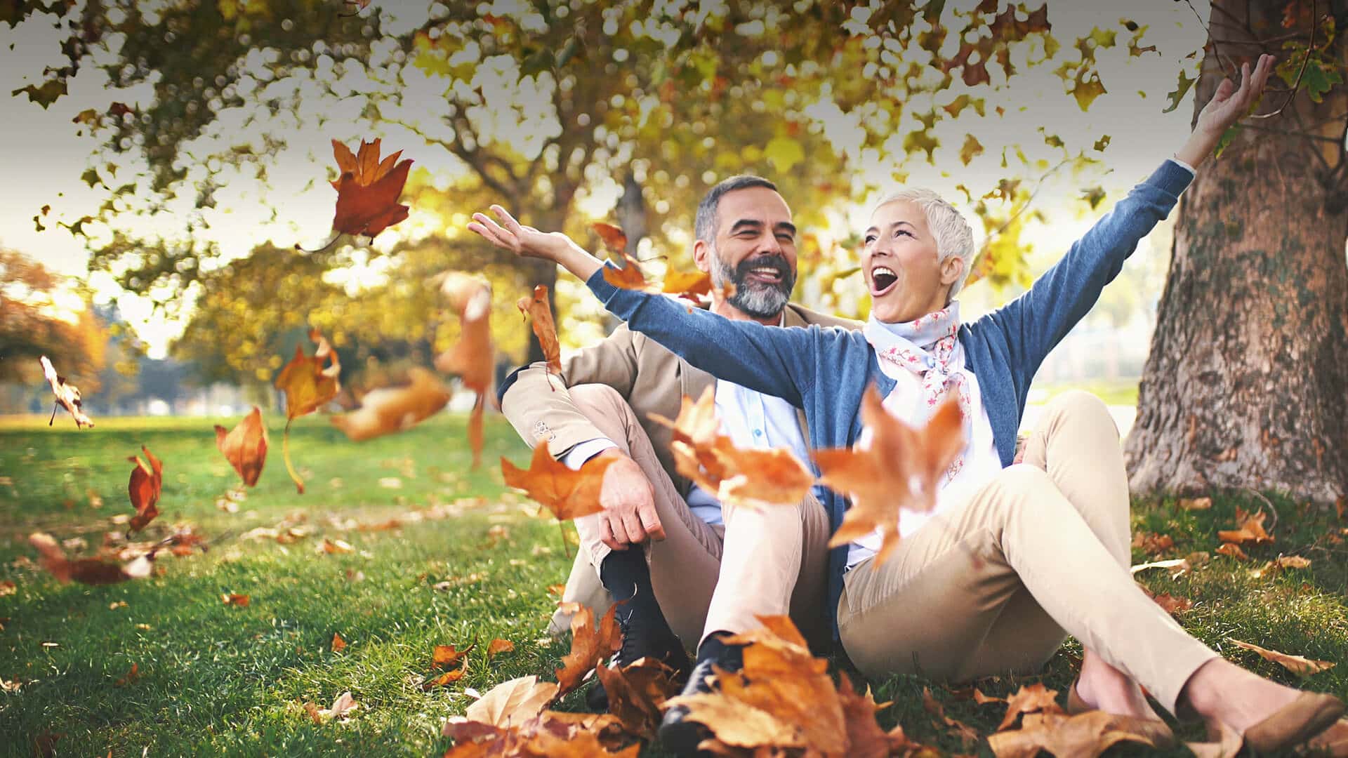 Dating over 50 symbolized by a happy man and woman sitting in the meadow of a park
